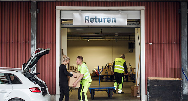 Person lämnar grejer till återbruk och medarbetare vid ReTuna tar emot.